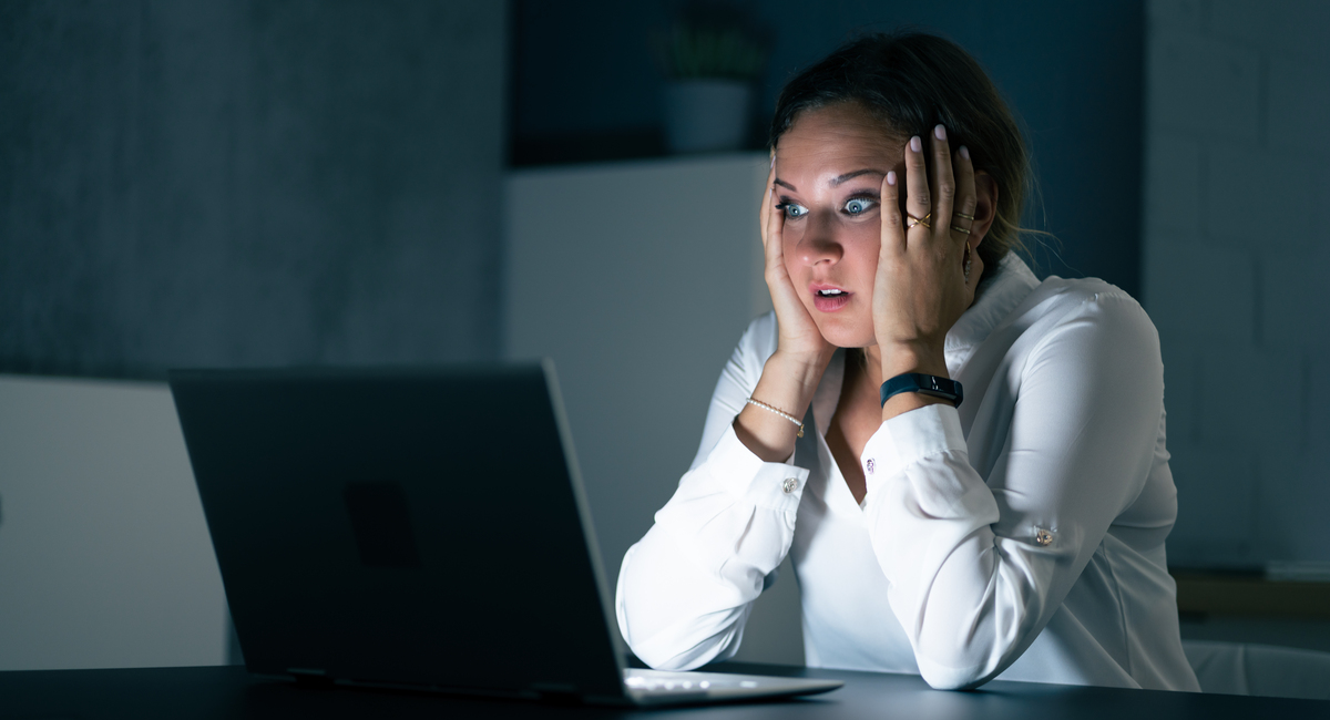 upset woman looking at computer screen at night